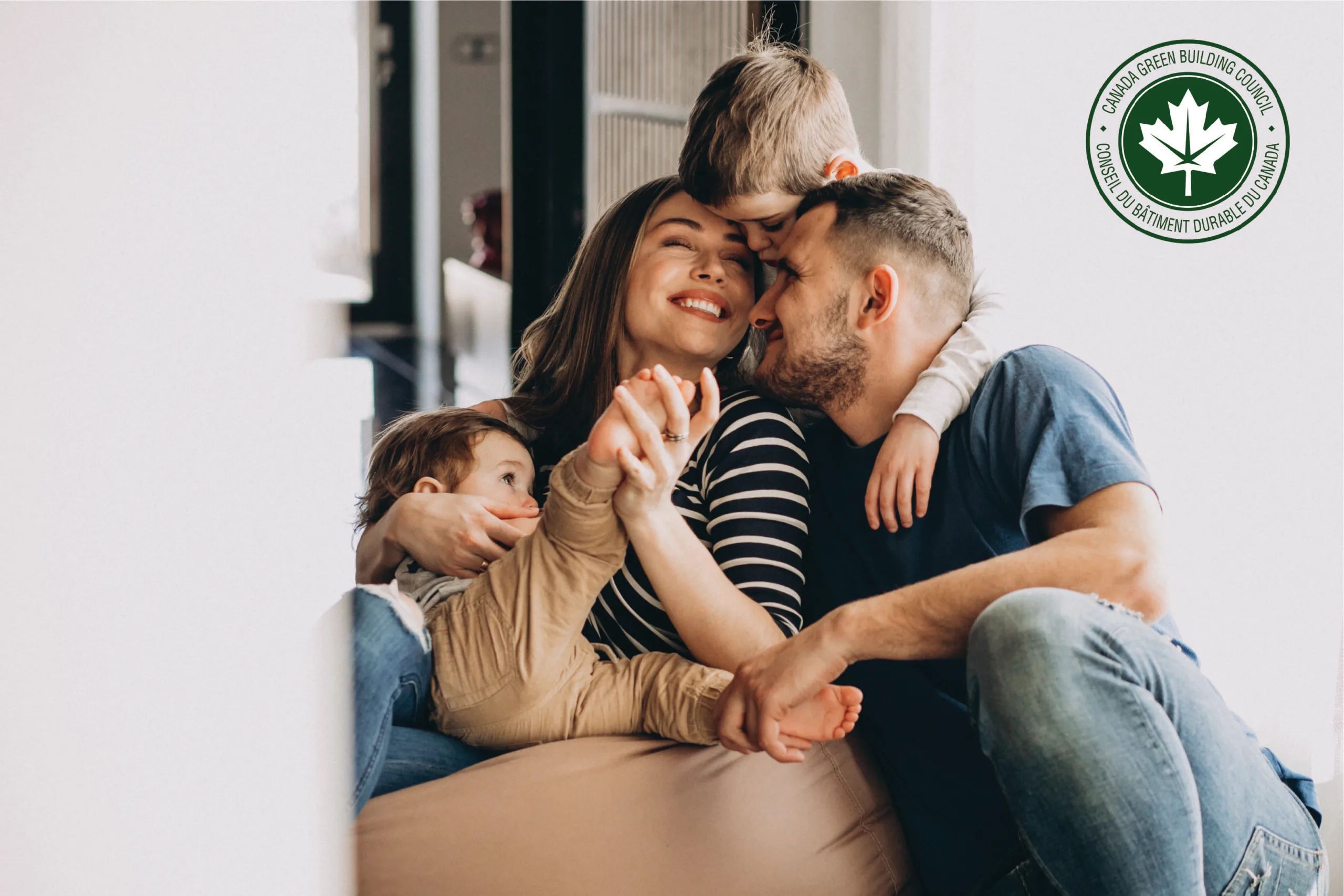 Happy family with two young children hugging in front of Canada Green Building Council logo