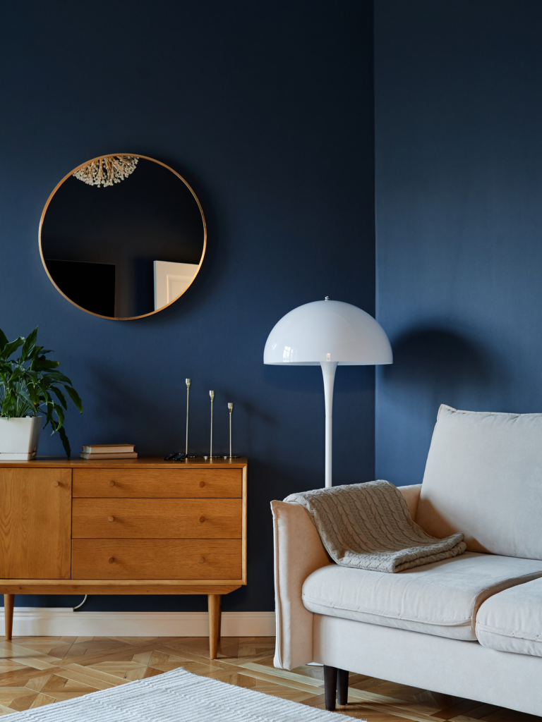 Living Room Paint Colors 1 Living room with navy walls, wooden sideboard, sofa, and floor lamp
