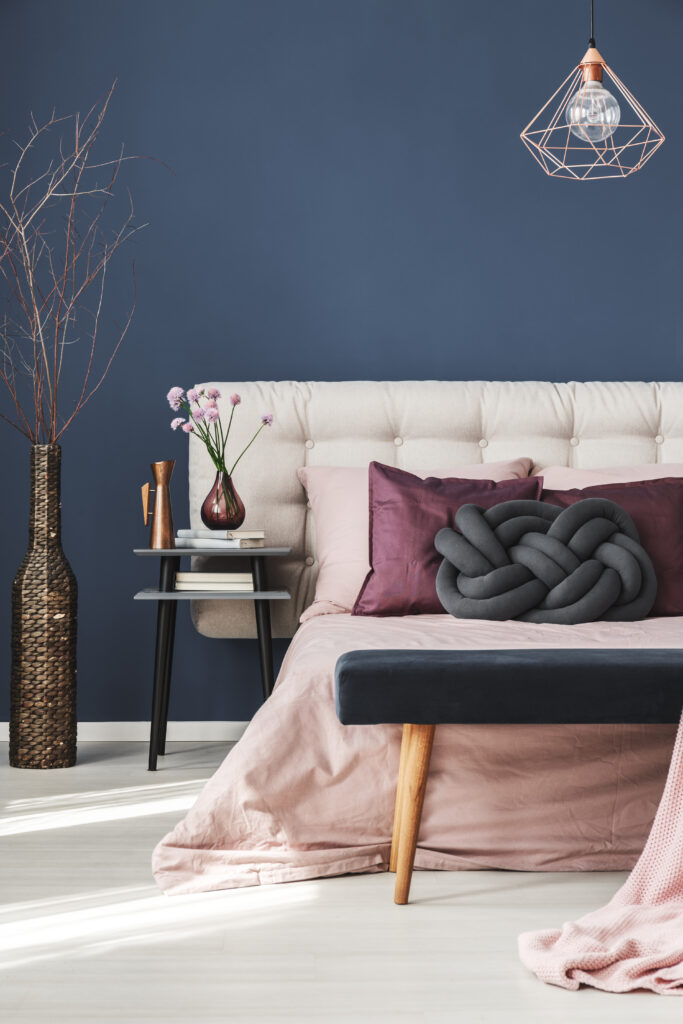 Bedroom Paint Colors 1 Elegant bedroom with plush tousled pink bedding, dark accent pillows, and rattan vase.